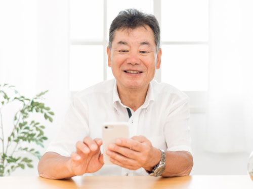 おじさんがスマホ触っている写真